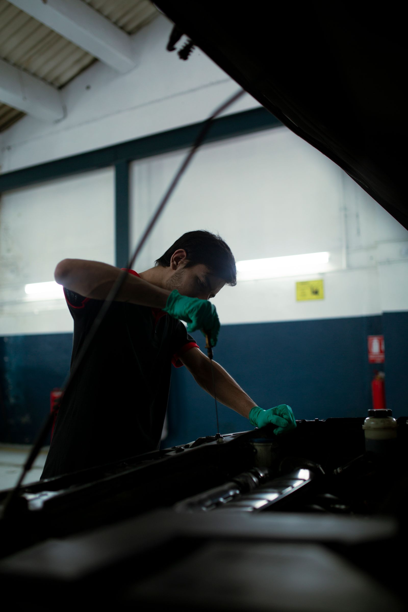 Mecanico revisando el nivel y estado del aceite del motor con la varilla medidora